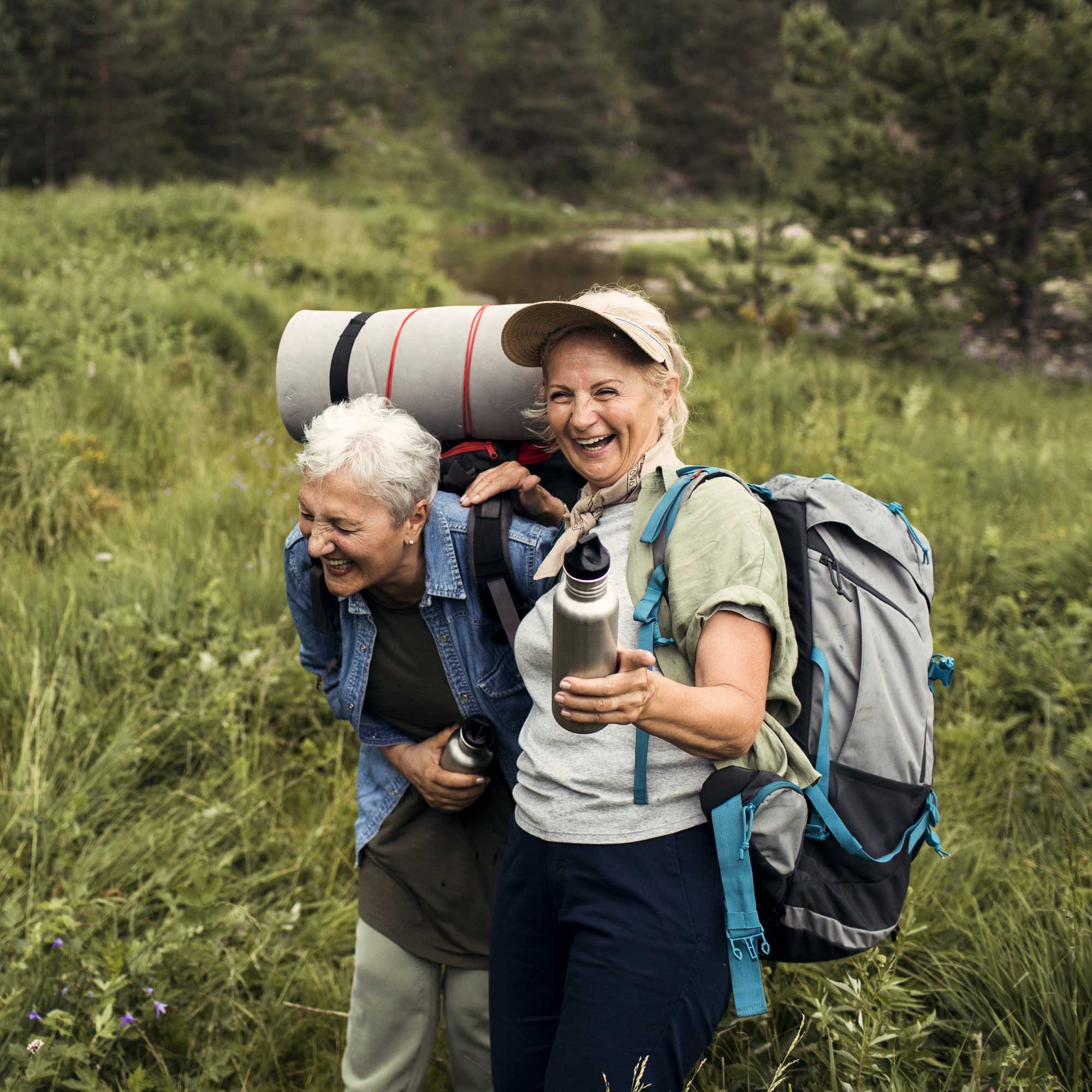 Två äldre kvinnor med ryggsäckar vandrar i naturern